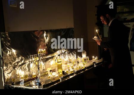 Jerusalem. 19.. Dezember 2022. Ein Mann zündet am 19. Dezember 2022 in Jerusalem in der ultra-orthodoxen jüdischen Gemeinde Mea Shearim Kerzen für das Festival von Hanukka an. Kredit: Gil Cohen Magen/Xinhua/Alamy Live News Stockfoto