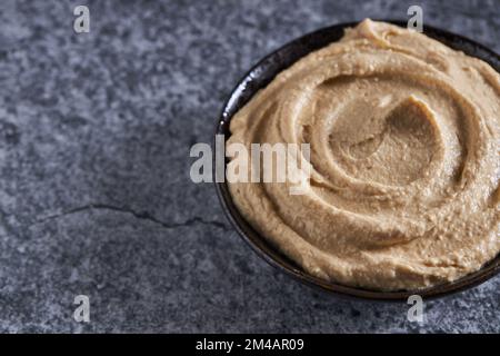 Von oben mit frischem Hummus serviert in einer Schüssel auf einem grauen Marmortisch in der Küche Stockfoto