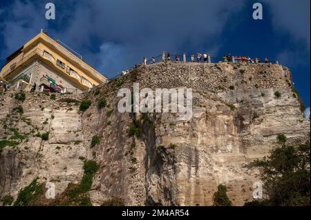 Urlauber, die sich auf die Geländer dieses belvedere in der Altstadt von Tropea auf den Klippen lehnen, an der Westküste von Kalabrien, Süditalien, genießen spektakuläre Aussichten über das türkisfarbene Tyrrhenische Meer und, an klaren Tagen, können sogar die vulkanische Felsformation von Stromboli sehen, etwa 37 Meilen (60 km) Nach Westen. Stockfoto