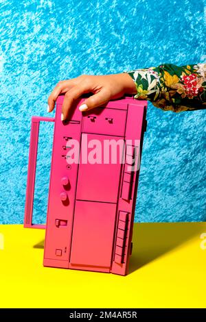 Eine Frau mit einem rosa Retro-Rekorder auf einer gelben Oberfläche Stockfoto