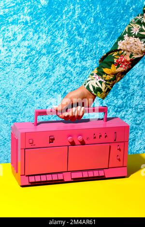 Eine Frau mit einem rosa Retro-Rekorder auf einer gelben Oberfläche Stockfoto