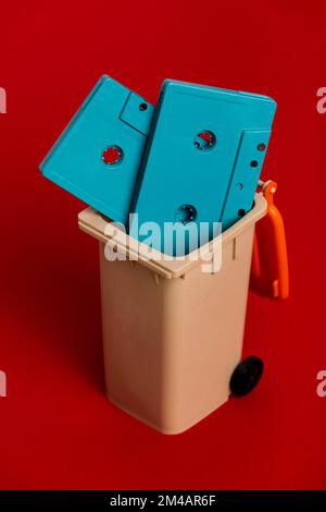 Hoher Winkel von Retro-blauen Bandkassetten in braunem Kunststoffbehälter vor rotem Hintergrund Stockfoto