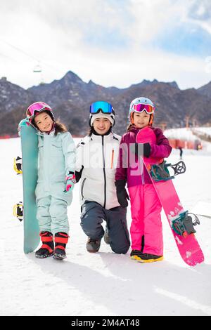 Fröhliche chinesische Kinder mit ihrem Bus im Skigebiet Stockfoto