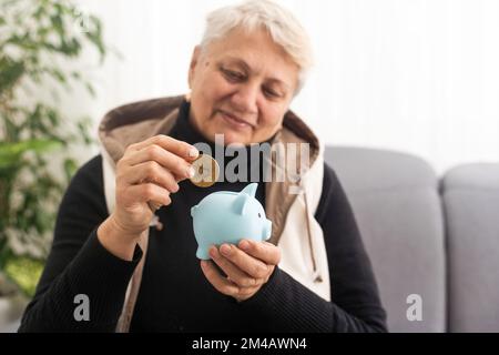 Geldverwaltungskonzept. Eine ältere Frau hält ein Sparschwein Stockfoto