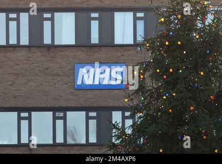 Nottingham, Nottinghamshire, Großbritannien. 20.. Dezember 2022 Ein NHS-Schild hängt hinter einem Weihnachtsbaum in der Nähe eines Schwesternstreiks vor dem QueenÕs Medical Centre, nachdem die Schwestern in England, Wales und Nordirland den zweiten von zwei tagelangen Streiks über die Bezahlung begannen. Kredit: Darren Staples/Alamy Live News. Stockfoto