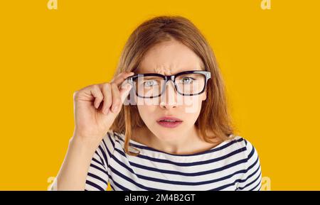 Unzufriedene junge Frau hat einen fokussierten Blick und starrt dich mit voller Brille an. Stockfoto