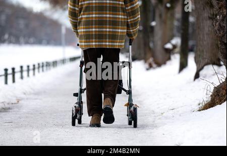 München, Deutschland. 20.. Dezember 2022. Ein Mann läuft mit seinem Roller auf einem eisigen Bürgersteig am Nymphenburger Kanal. Kredit: Sven Hoppe/dpa/Alamy Live News Stockfoto