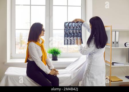 Arztin, die ihrem Patienten in der Arztpraxis Röntgenaufnahmen vorstellt Stockfoto