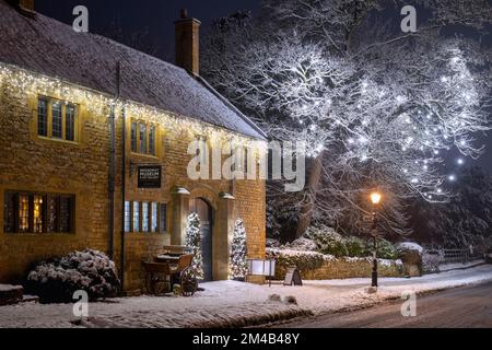 Broadway-Museum und Weihnachtsbaumdekorationen bei Nacht im Schnee. Broadway, Cotswolds, Worcestershire, England Stockfoto