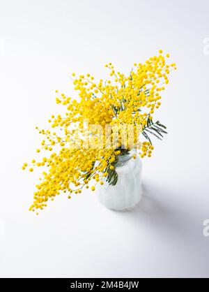 Ein Strauß gelber Mimosablüten steht in einer Glasvase auf weißem Hintergrund. Konzept vom 8. März, fröhlicher Frauentag. Speicherplatz kopieren Stockfoto