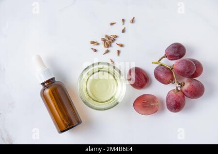 Die flache Lage besteht aus natürlichem Traubensamenöl auf weißem Marmorhintergrund. Natürliche Kosmetik, gesunder Lebensstil. Draufsicht und Kopierbereich Stockfoto