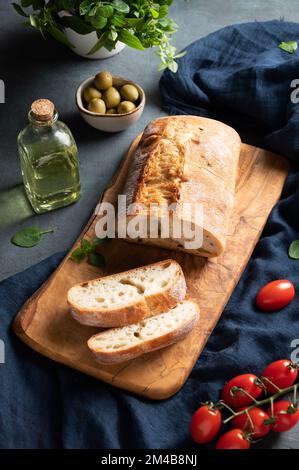 Italienische Ciabatta-Brotscheiben mit Tomaten, Basilikum und Oliven auf dunklem Hintergrund. Draufsicht. Stockfoto
