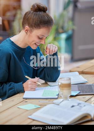 Frau, Laptop und Notebook, die in einem Café, Café oder Restaurant für eine Universität, ein College oder ein Schulstudium schreibt. Lächeln, glücklich oder e-learning-Schüler Stockfoto