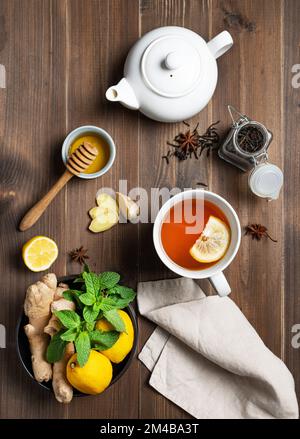 Immunsystem Booster - Tee mit Ingwer, Honig, Zitrone, Minze und Gewürzen auf dunklem Holzhintergrund. Das Konzept der gesunden Ernährung. Draufsicht. Stockfoto