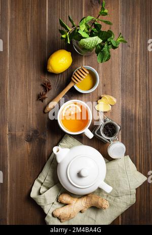 Immunsystem Booster - flacher Laientee mit Ingwer, Honig, Zitrone, Minze und Gewürzen auf dunklem Holzhintergrund. Das Konzept der gesunden Ernährung. Draufsicht. Stockfoto