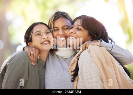 Freundinnen, umarmen und lächeln Sie im Park, um glücklich zu sein, unterstützen und entspannen Sie sich in der Sonne beim Treffen der besten Freunde. Frauengruppe, glücklich und liebenswürdig Stockfoto