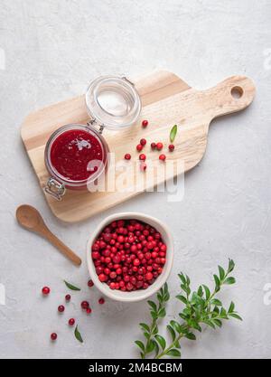 Saftige Waldlingbeere mit handgemachter Marmelade in einem Glas auf weißem Tisch und Schneidebrett. Konzept hausgemachte gesunde Lebensmittel. Ansicht von oben und Bild des Bereichs kopieren Stockfoto