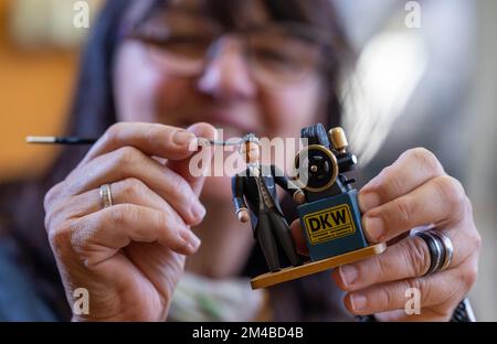 20. Dezember 2022, Sachsen, Seiffen: In der Werkstatt des Walter Werner Kunsthandwerks in Seiffen malt Annette Reichl Holzfiguren des DKW-Gründers Jörgen Skafte Rasmussen. Anlässlich der 100-jährigen Produktion der DKW-Motorradserie hat das Holzkunstgeschäft in seinem Abschnitt „sächsische Originale“ eine kleine Zahl von acht Zentimetern herausgegeben. Der ersten Reihe von 100 Zahlen folgen weitere. Vor 100 Jahren rollten die ersten seriengefertigten Motorräder bei DKW vom Band. Ein paar Jahre später wurde das Werk in Zschopau zum weltweit größten Hersteller von Zweirädern. Foto: Hendri Stockfoto