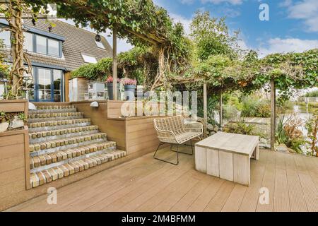 Eine Terrasse mit vielen Pflanzen an der Seite und Treppen, die in die obere Ebene führen, es gibt einen Sitzbereich im Freien Stockfoto