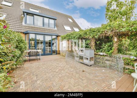 Ein Haus mit Außenterrasse und Gartenbereich im Vorderbereich - Bild wird von außen aufgenommen, mit Blick auf die Hintertür Stockfoto