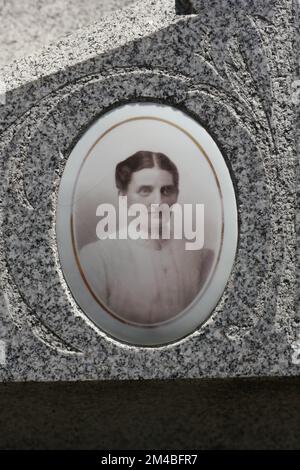 Ein Porträt einer erwachsenen Frau, geklebt an einen Grabstein, als Erinnerung an die Person. Stockfoto