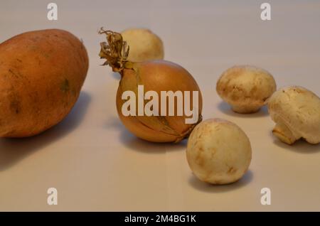 Loses Gemüse auf weißem Hintergrund. Kartoffeln, Zwiebeln, Pilze. Bestandsbild. Stockfoto