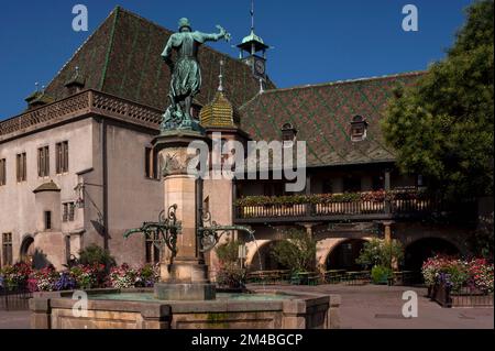 Bronzebrunnen-Statue des kaiserlichen Kommandanten Lazarus von Schwendi (1522-1583) von Frédéric-Auguste Bartholdi, Designer der New Yorker Freiheitsstatue, gegenüber dem alten Zollhaus oder Koihhus, erbaut 1480, auf der Place de l'Ancienne Douane in Colmar, Elsass, Grand Est, Frankreich. Das Koifhus unter einem gemusterten Schindeldach im Burgundianischen Stil ist Colmars ältestes öffentliches Gebäude. Stockfoto