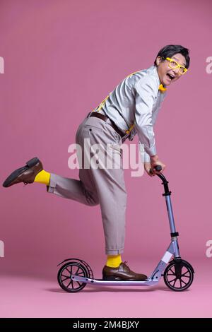 Fröhlicher, älterer chinesischer Mann, der Roller fährt Stockfoto