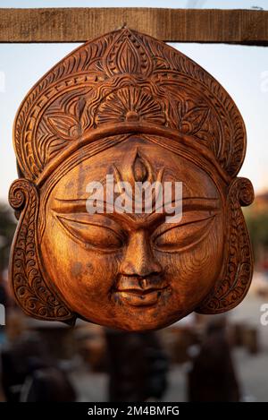 Die wunderschöne handgefertigte Holzskulptur der Göttin devi Durga wird in einem Geschäft mit verschwommenem Hintergrund zum Verkauf ausgestellt. Indische Kunst und Kunsthandwerk. Stockfoto