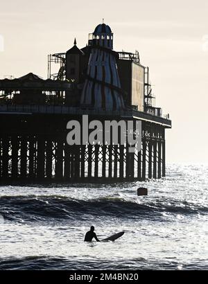 Brighton UK 20. . Dezember 2022 - Ein Surfer macht das Beste aus einem sonnigen Tag in Brighton in der Nähe des Piers , da das Vereinigte Königreich nach den Temperaturen unter Null in der vergangenen Woche eine viel wärmere Witterung genießt . : Credit Simon Dack / Alamy Live News Stockfoto