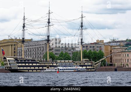 Touristen fahren mit einem Vergnügungsboot auf der Newa vor der Kulisse eines alten Schoners, der am Petrovskaya-Ufer in St. Petersburg, Russ, vor Anker liegt Stockfoto