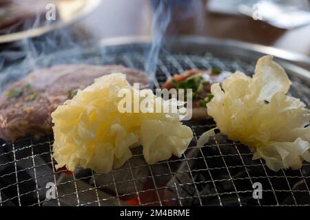 Köstliches Schweinefleisch mit tremella-Pilzen auf dem Grill. Rauch vom Grillfleisch Stockfoto