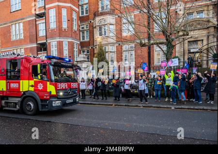 London, Großbritannien. 20.. Dezember 2022. Ein vorbeifahrender Feuerwehrwagen der Londoner Feuerwehr salutiert den Protest mit blauen Lichtern, wenn er vorbeifährt - Eine Streikposte von Krankenschwestern vor dem Royal Marsden Hospital als Teil des vom RCN organisierten Streiks über Krankenpflegegeld. Kredit: Guy Bell/Alamy Live News Stockfoto