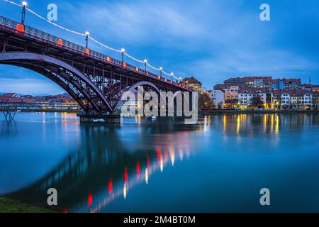 Die Stadt Maribor und Drava River in der Abenddämmerung. Foto aufgenommen am 1.. Dezember 2022 in Maribor, Region Niedersteiermark, Slowenien. Stockfoto