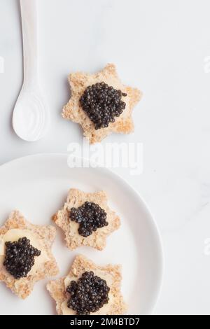 Schwarze Kaviar-Vorspeisen Brotsterne mit Butter auf weißem Hintergrund Draufsicht Vertikal Stockfoto