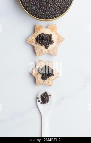 Schwarze Kaviar-Vorspeisen Brotsterne mit Butter auf weißem Hintergrund Draufsicht Vertikal Stockfoto