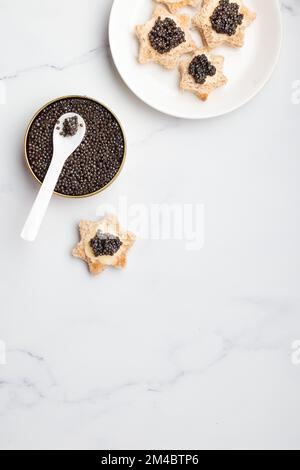 Schwarze Kaviar-Vorspeisen Brotsterne mit Butter auf weißem Hintergrund Draufsicht Vertikal Stockfoto