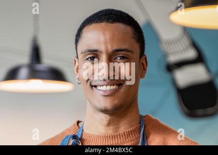 Lächelnder Besitzer oder Kellner in Arbeitsuniform stehen in moderner Cafeteria oder Restaurant Pub - Stellenangebot Konzept - Arbeiten in Catering Stockfoto