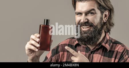 Kunststoffbehälter mit Shampoo. Junger gutaussehender Mann, der Creme Lotion aufträgt Stockfoto
