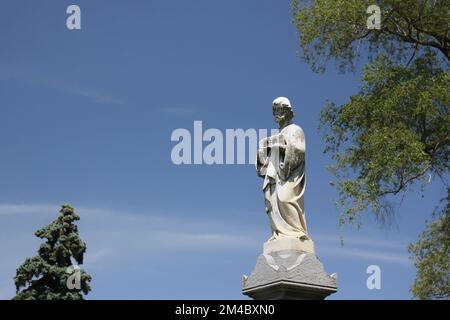 Wunderschöne Steinstatue von St. Joseph, die vor einem klaren blauen Himmel steht. Stockfoto