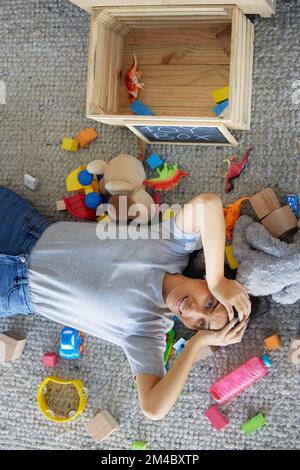 Stress, Mutter oder Spielzeug in einem chaotischen Wohnzimmer für Frühjahrsputz, Housekeeping oder ordentliche Wartung in der Draufsicht. Angst, psychische Gesundheit oder Burnout-mom Stockfoto