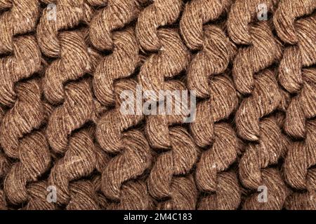 Details des handgefertigten Strickmusters. Hintergrund und Textur von gestricktem Wolle- oder Baumwollgewebe. Nahaufnahme. Braune Farbe. Stockfoto