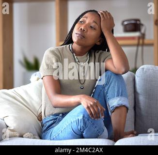 Schwarze Frau, Sofa und Stress mit Sorge, Denken und traurig im Wohnzimmer mit Angst vor der Zukunft. Afrikanische Frau, Sitzecke und Lounge-Sofa mit Stockfoto