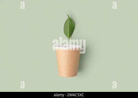 Umweltfreundliche Kaffeetasse mit grünem Hintergrund. Draufsicht. Brauner Pappbecher ohne Kunststoff mit Blatt. Minimalismus. Recycelbare Verpackungen Für Street Food. Null wa Stockfoto