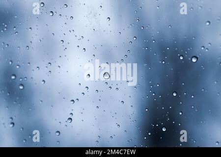 An regnerischen Tagen befinden sich Wassertropfen auf einem Fensterglas, abstrakte Hintergrundstruktur Stockfoto