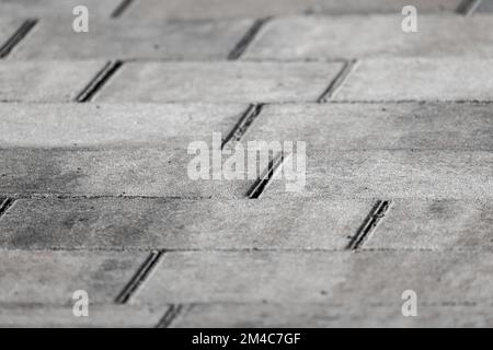 Grauer Betonhintergrund mit Kopfsteinpflaster, Asphaltplatten Nahaufnahme mit selektivem Weichzeichner Stockfoto