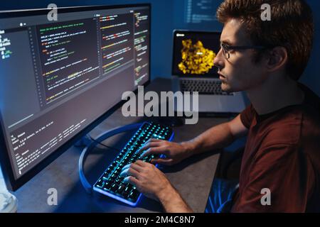 Profilansicht der Programme junger Entwickler im Home-Office, Mann im Hemd und mit Brille, der Code auf einem pc schreibt und die Datenbank überprüft. Programmentwicklung und datenwissenschaftliches Konzept Stockfoto