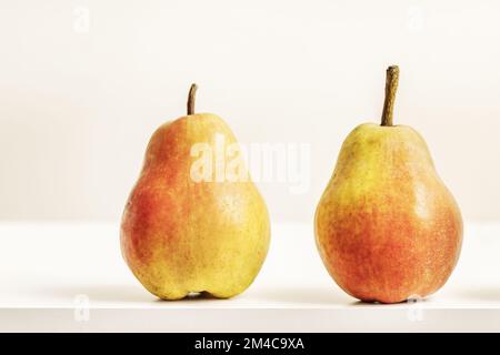 Zwei köstliche, reife Birnen auf einer weißen Oberfläche Stockfoto