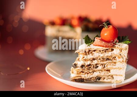 Ein Stück Kuchen mit Pilzen und Huhn garniert mit Tomaten und Salami Stockfoto