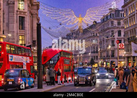 Regent Street, London: Einkaufsmassen zwischen hell beleuchteten Kaufhäusern und Weihnachtsverkehr unter Weihnachtslichtern Stockfoto